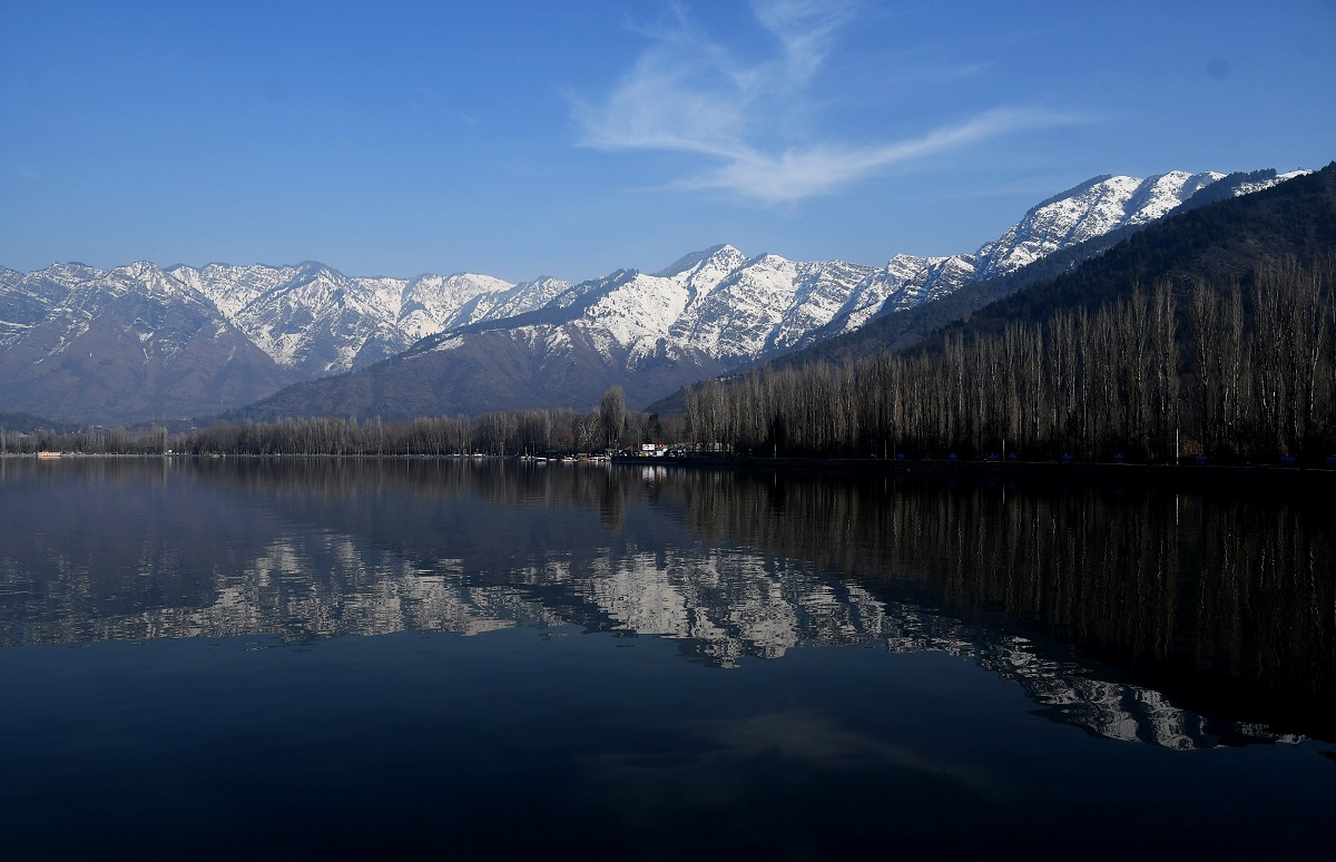 A scenic view of snow-covered mountains behind the Dal lake in Srinagar