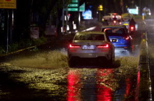 Vehicles move through a waterlogged road after heavy rainfall