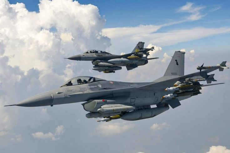 A grey fighter jet soaring high above clouds during a mission. - Photo Gallery