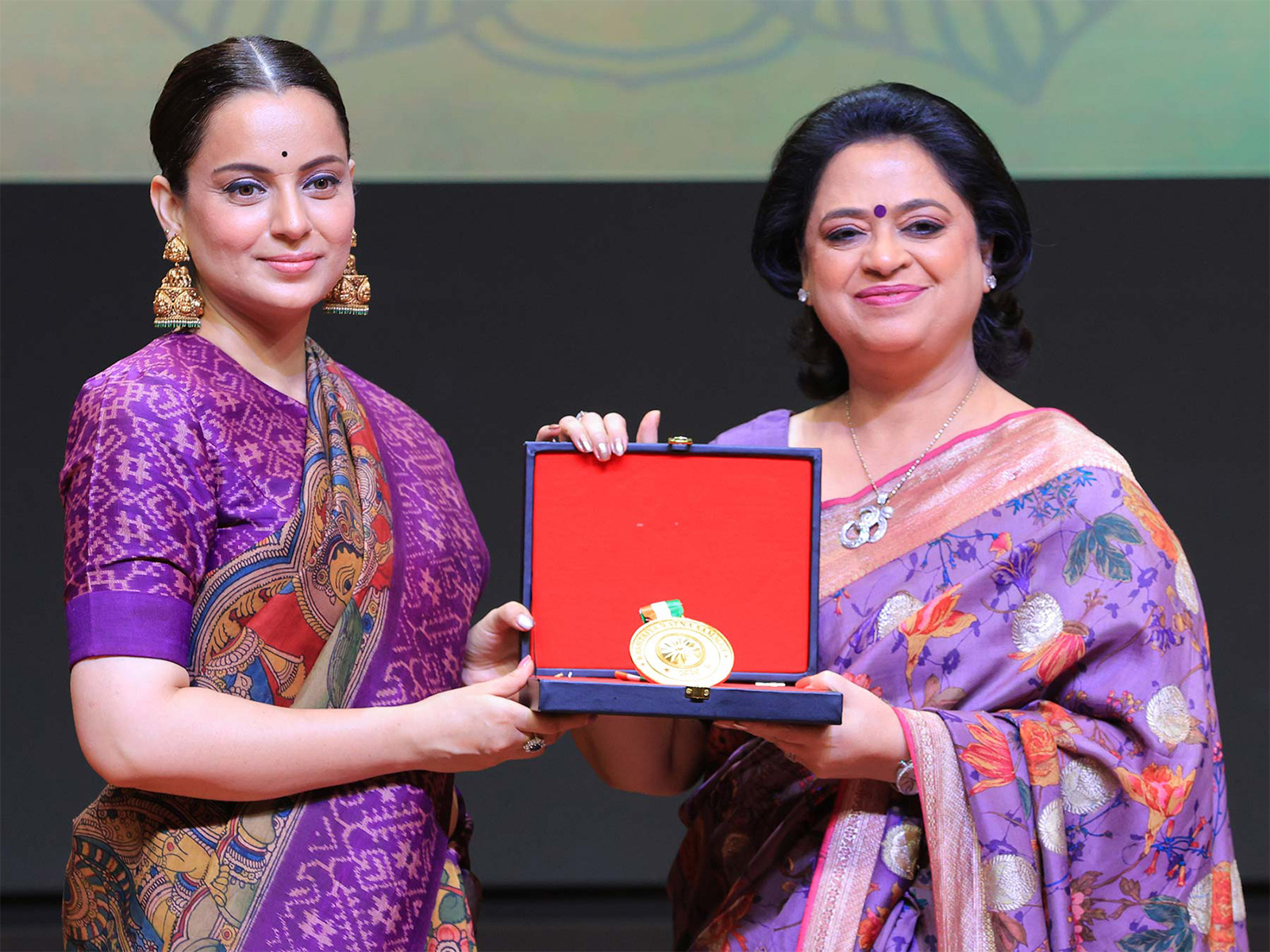 On stage at the Rashtriya Ratna Samman 2026, Ms. Sudha Gupta, Chairperson of Mothers Pride and Presidium Group of Schools, receives the 'Leave Your Mark - Global Life Skill Excellence Award' for Presidium Group of Schools from Ms. Kangana Ranaut.
