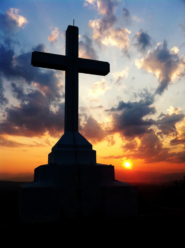 Wooden cross silhouetted against a sunrise sky