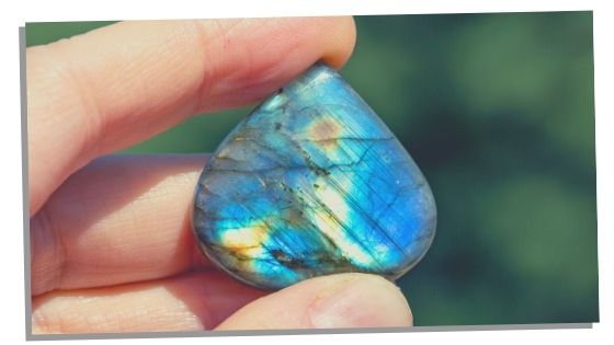 A hand holding Labradorite which balances the third eye chakra