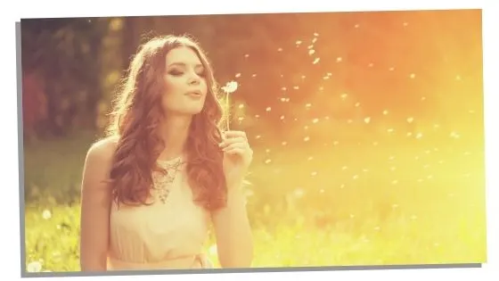 Woman blowing dandelion thinking of blessing