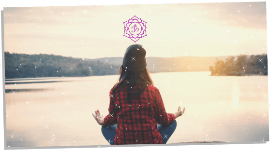 female sitting by lake doing crown chakra affirmations