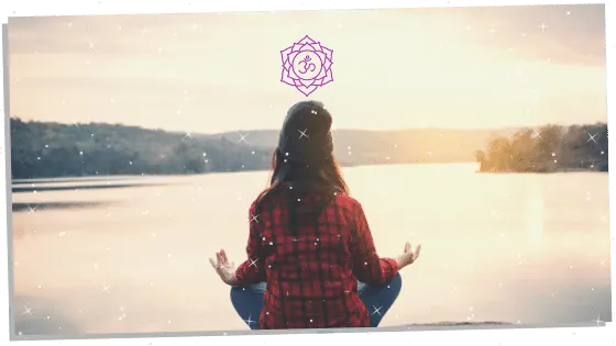 female sitting by lake doing crown chakra affirmations